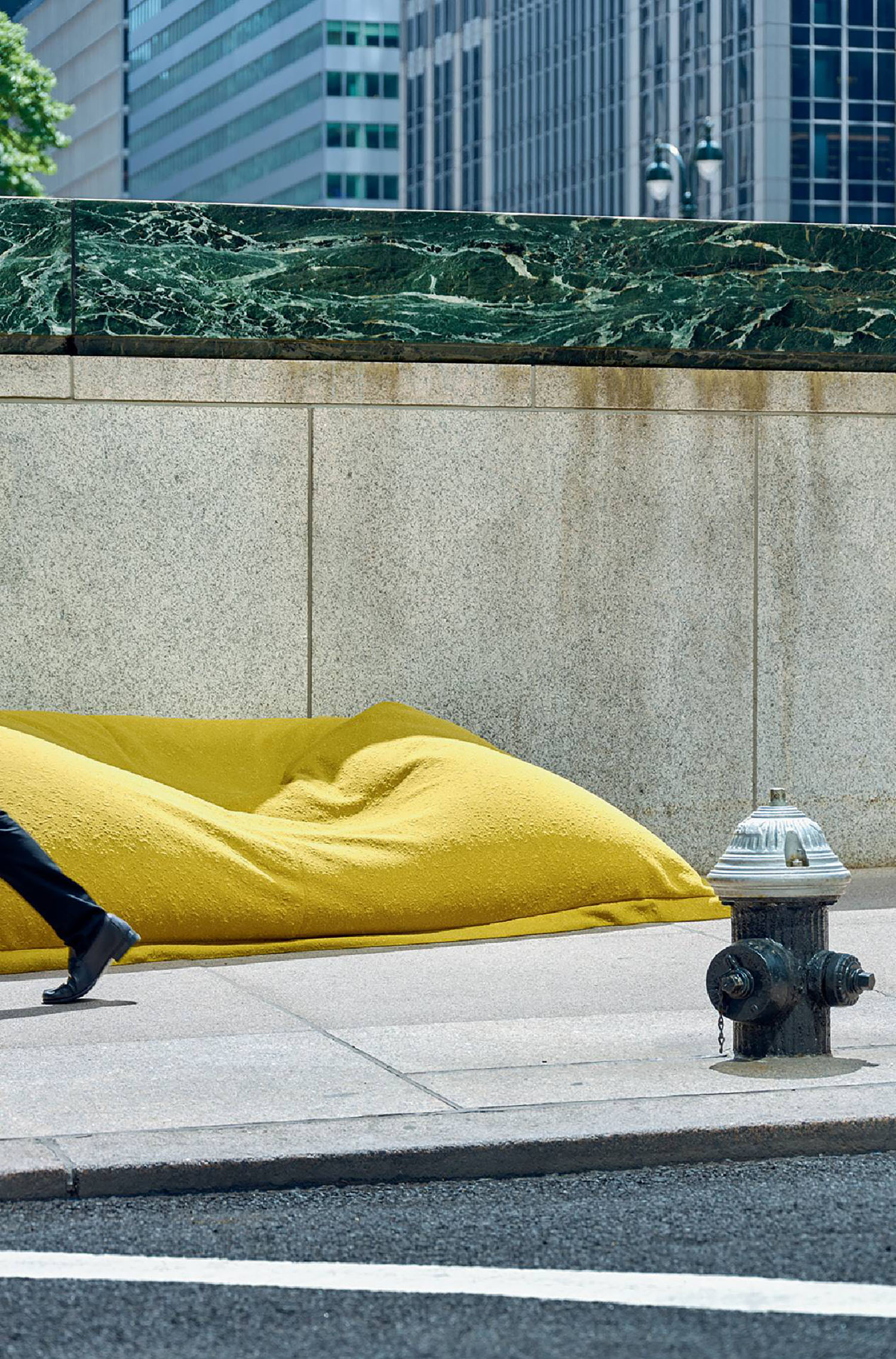 A man walking past a yellow blanket on the sidewalk.