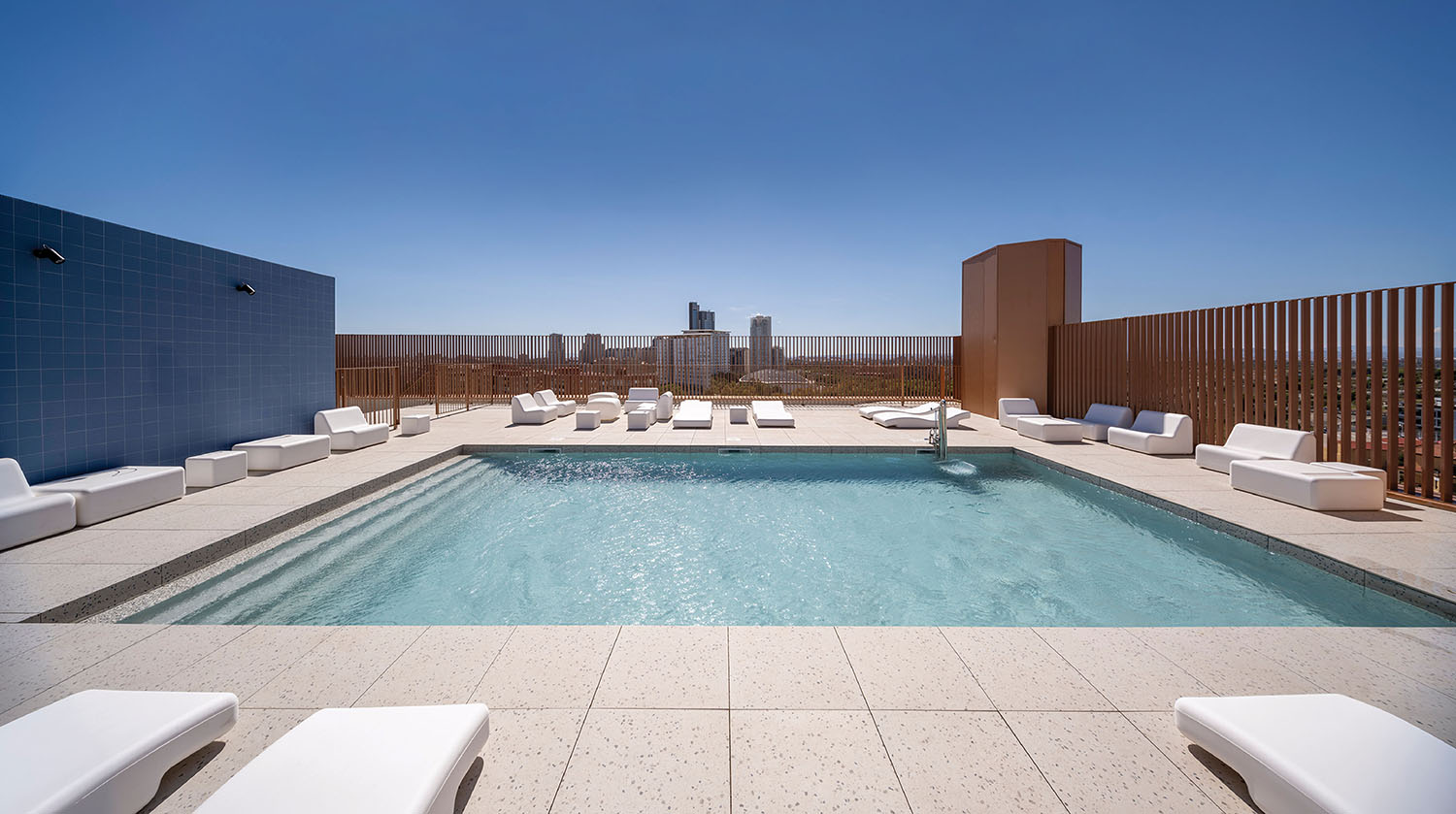 a pool with a white lounge chair and a blue sky