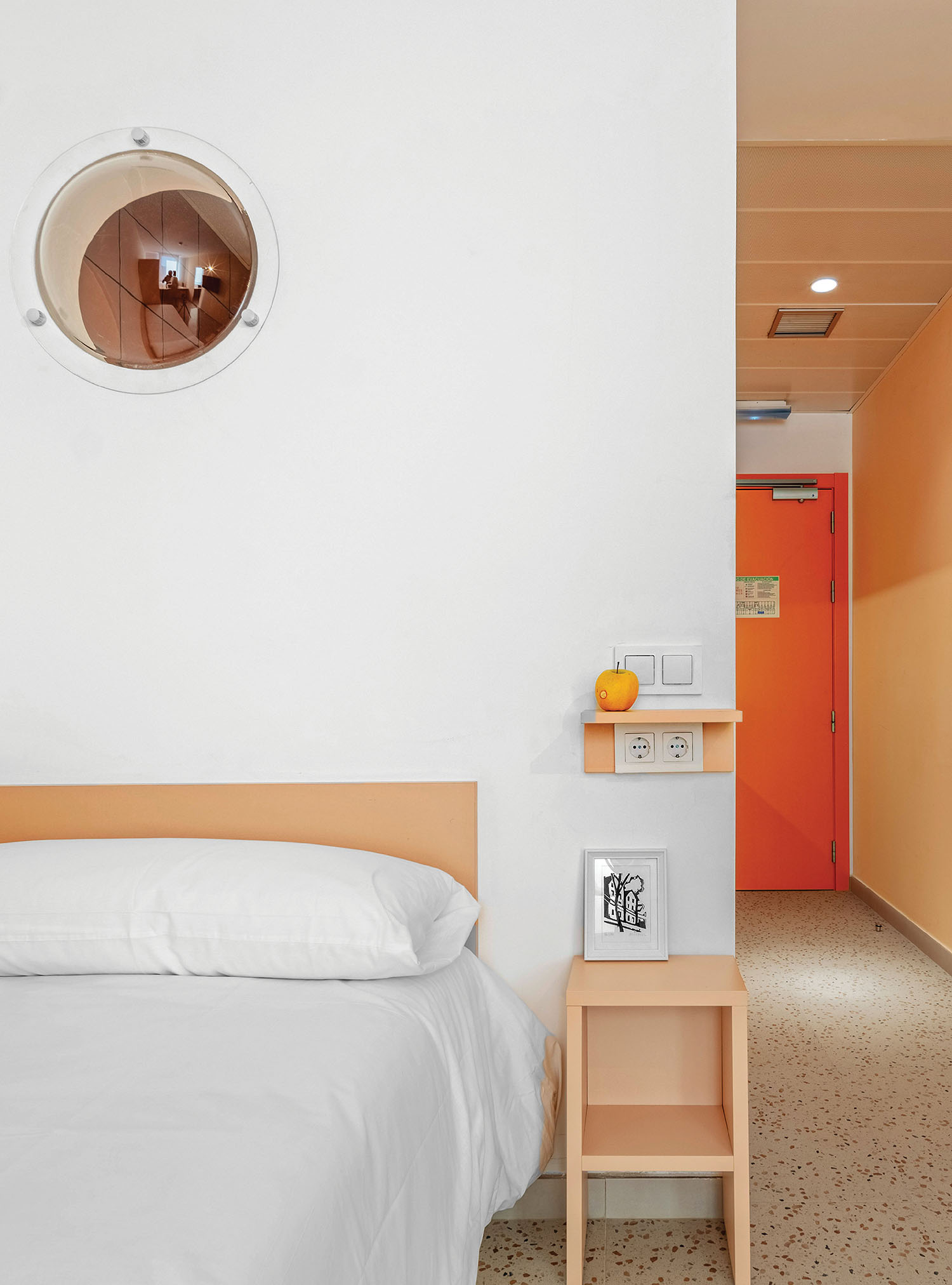 a bed with a white comforter and a round mirror