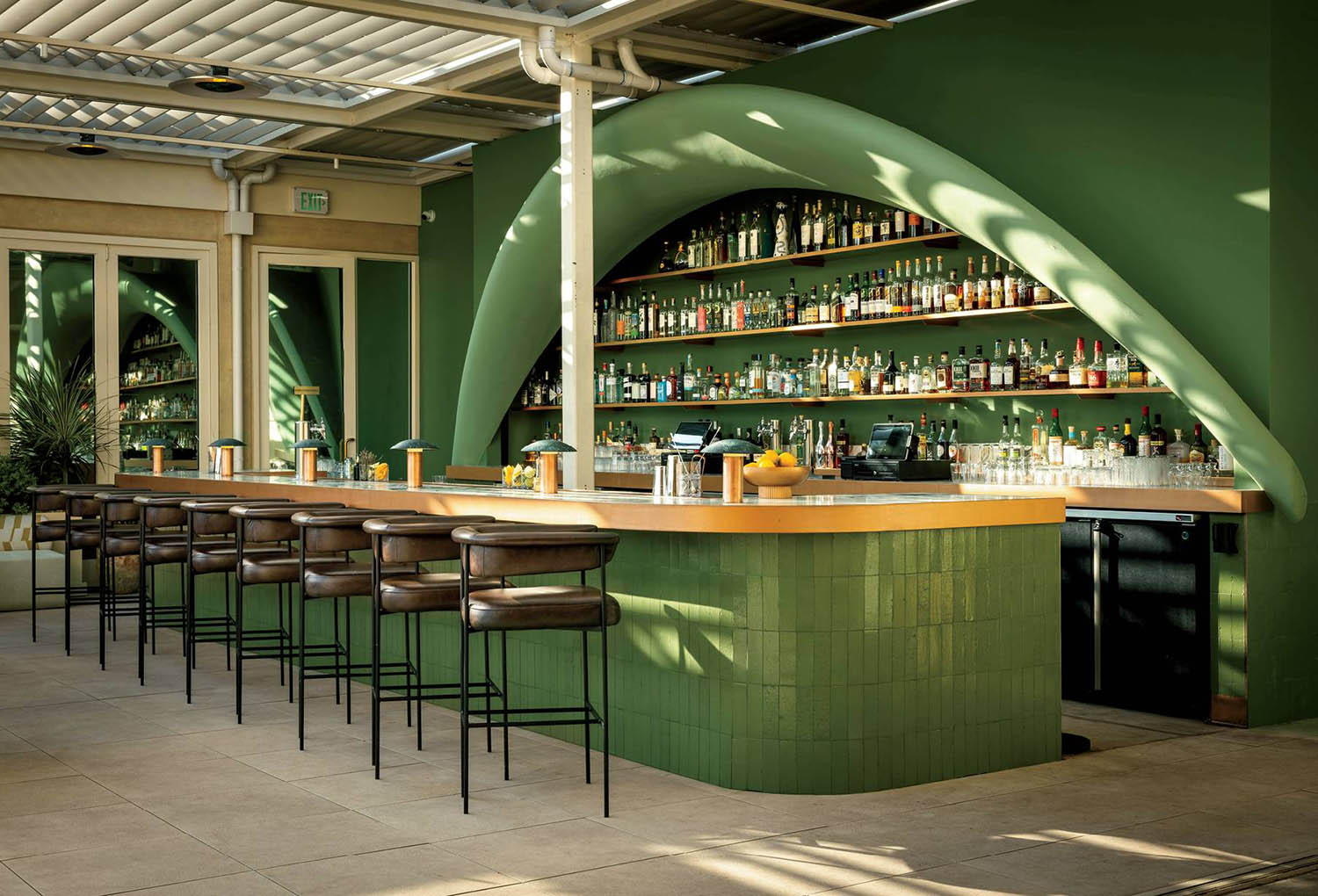 A bar with a green wall and a bar stool.