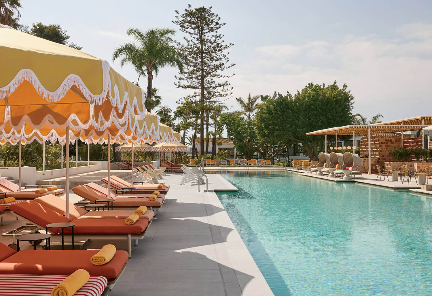 A pool with lounge chairs and umbrellas.