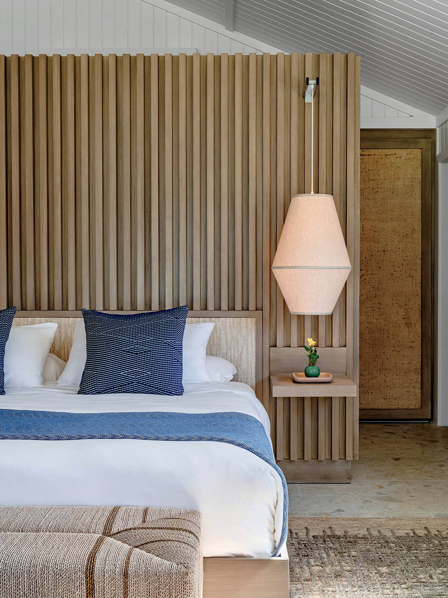 A bed with a blue blanket and pillows.